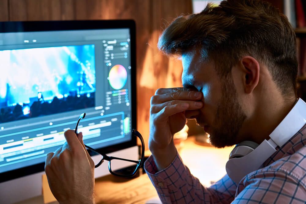 Boy rubbing their eyes while using a Computer.